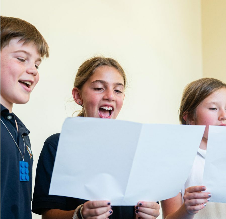 3 students reading paper and singing