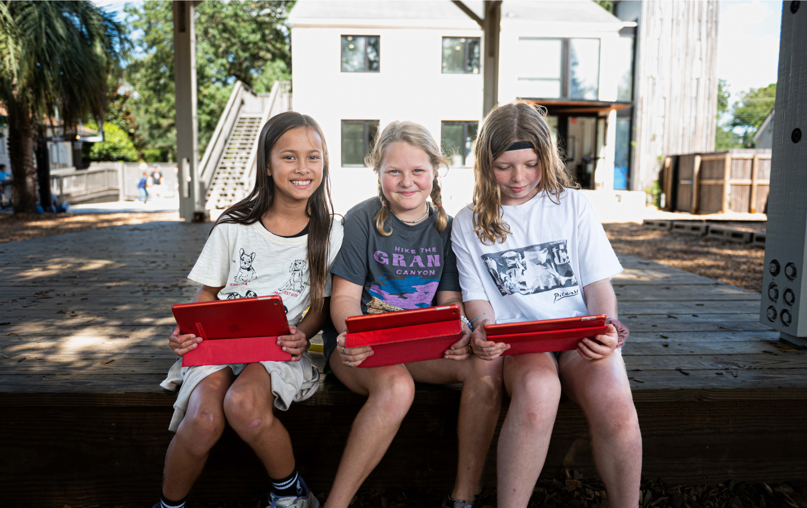 3 girls with red tablets sitting in gazebo