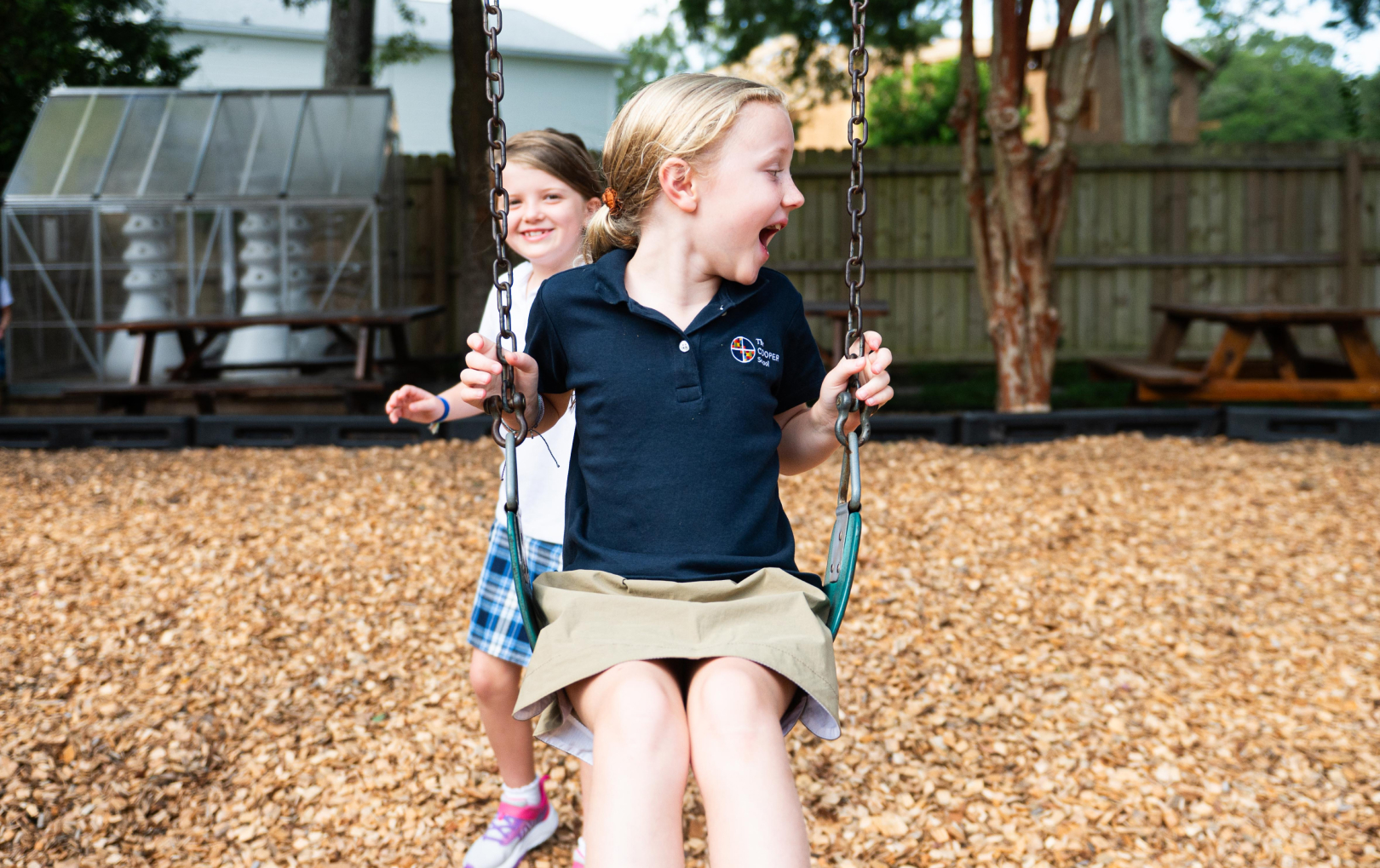 student laughing as they sit on a swing