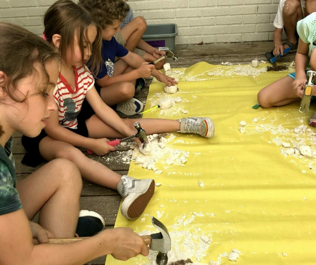 students smashing rocks on yellow mat