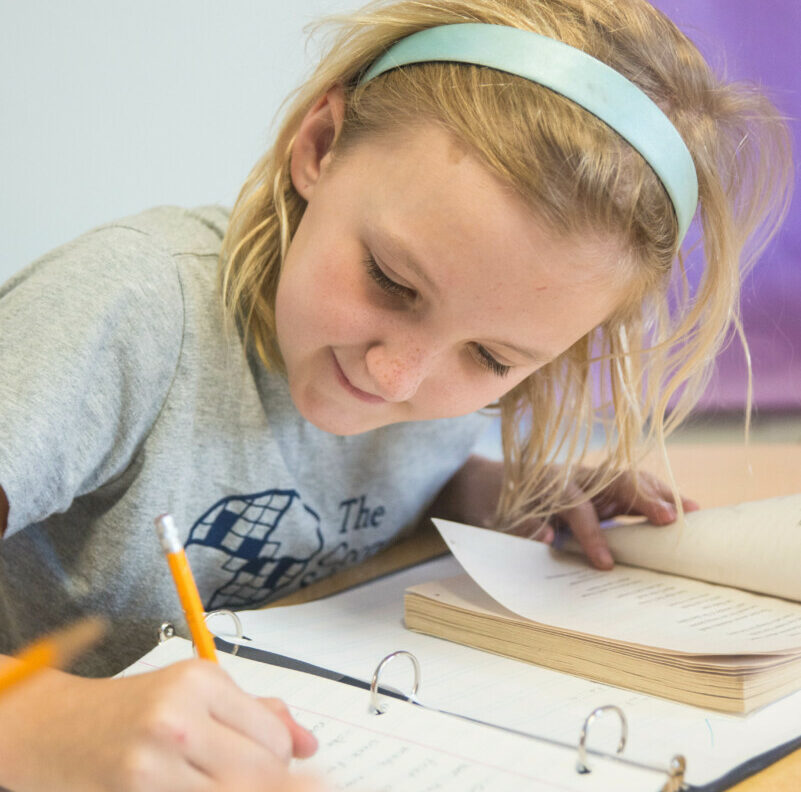 girl at desk writing in book